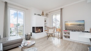 A modern living room with a fireplace, a sofa, a TV, and a view of the city.