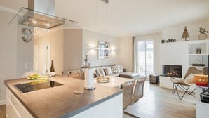A modern kitchen with a central island, a dining area with a sofa, and a living room with a fireplace.