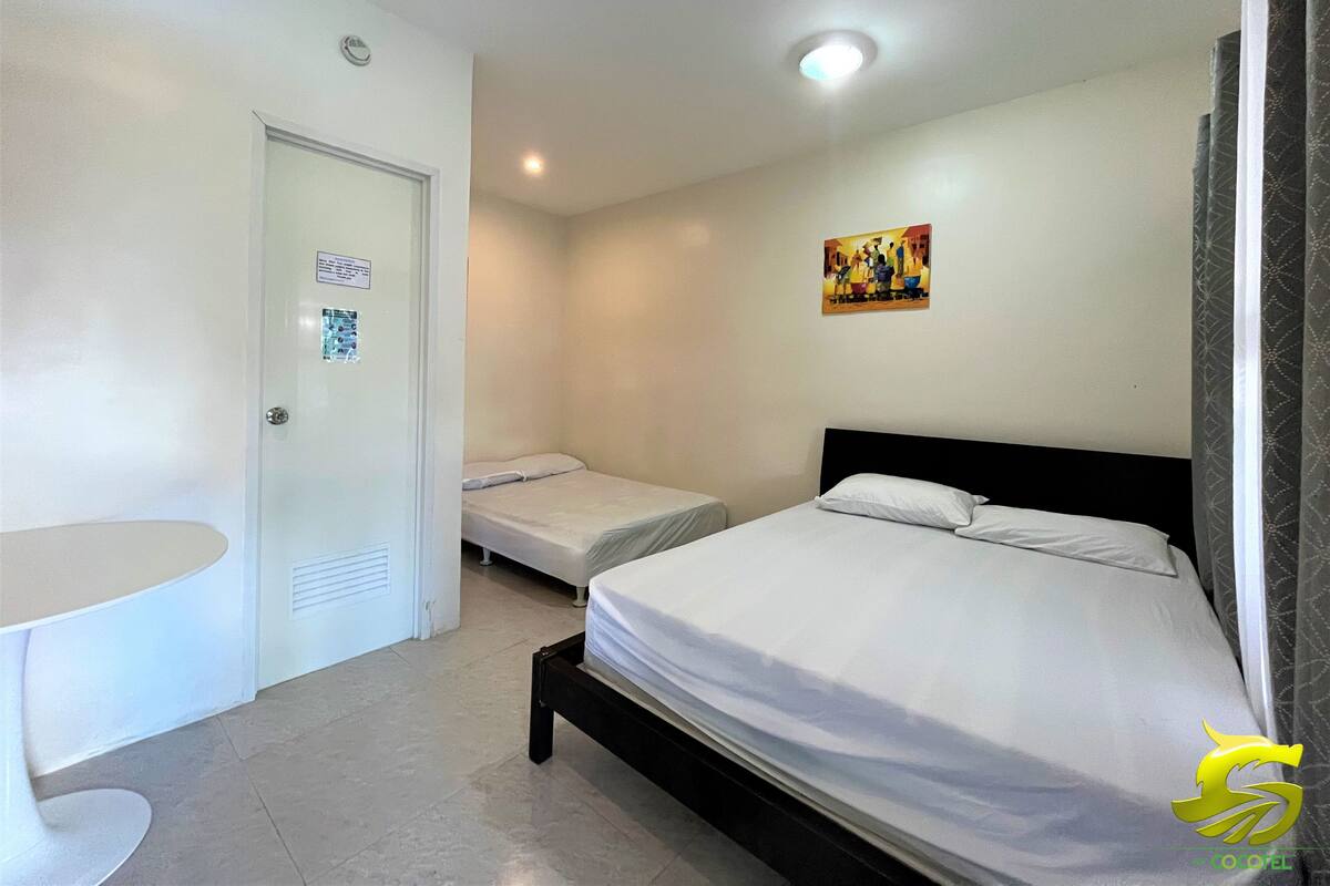 Une chambre d’hôtel avec deux lits simples, une petite table et un tableau au mur.