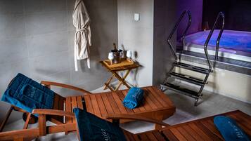 Relax in our serene spa area, featuring a comfortable lounge chair, a small table with refreshments, and a bathtub for ultimate relaxation.