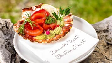 A plate with smoked salmon, caviar, and garnishes on a white plate with a note that reads "Zámeck Tréhost Chateau Tréhost".