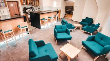 A modern lounge area with teal sofas, a coffee table, and a bar area with stools.