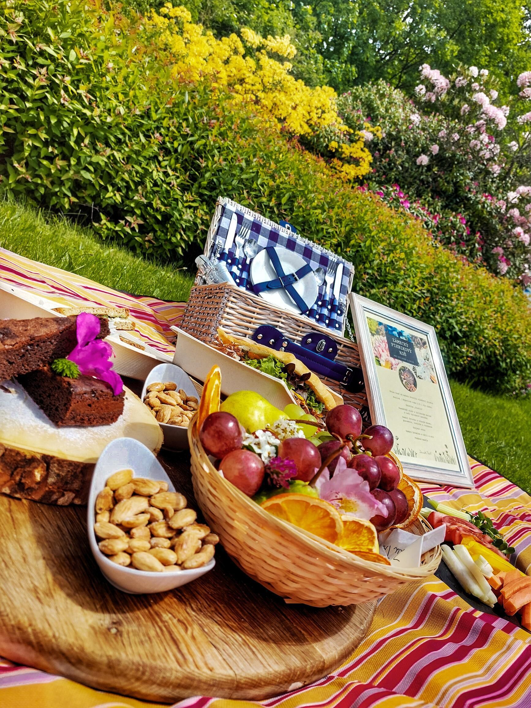 Un montaje para picnic con comida y un certificado sobre una manta en un jardín.