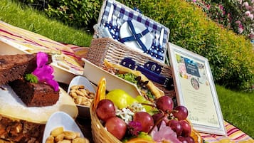 Un montaje para picnic con comida y un certificado sobre una manta en un jardín.