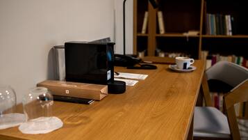 A wooden table with a coffee maker, a cup of coffee, a notebook, and a pair of glasses.