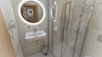A bathroom with a glass shower enclosure, a sink, and a mirror with a circular frame.