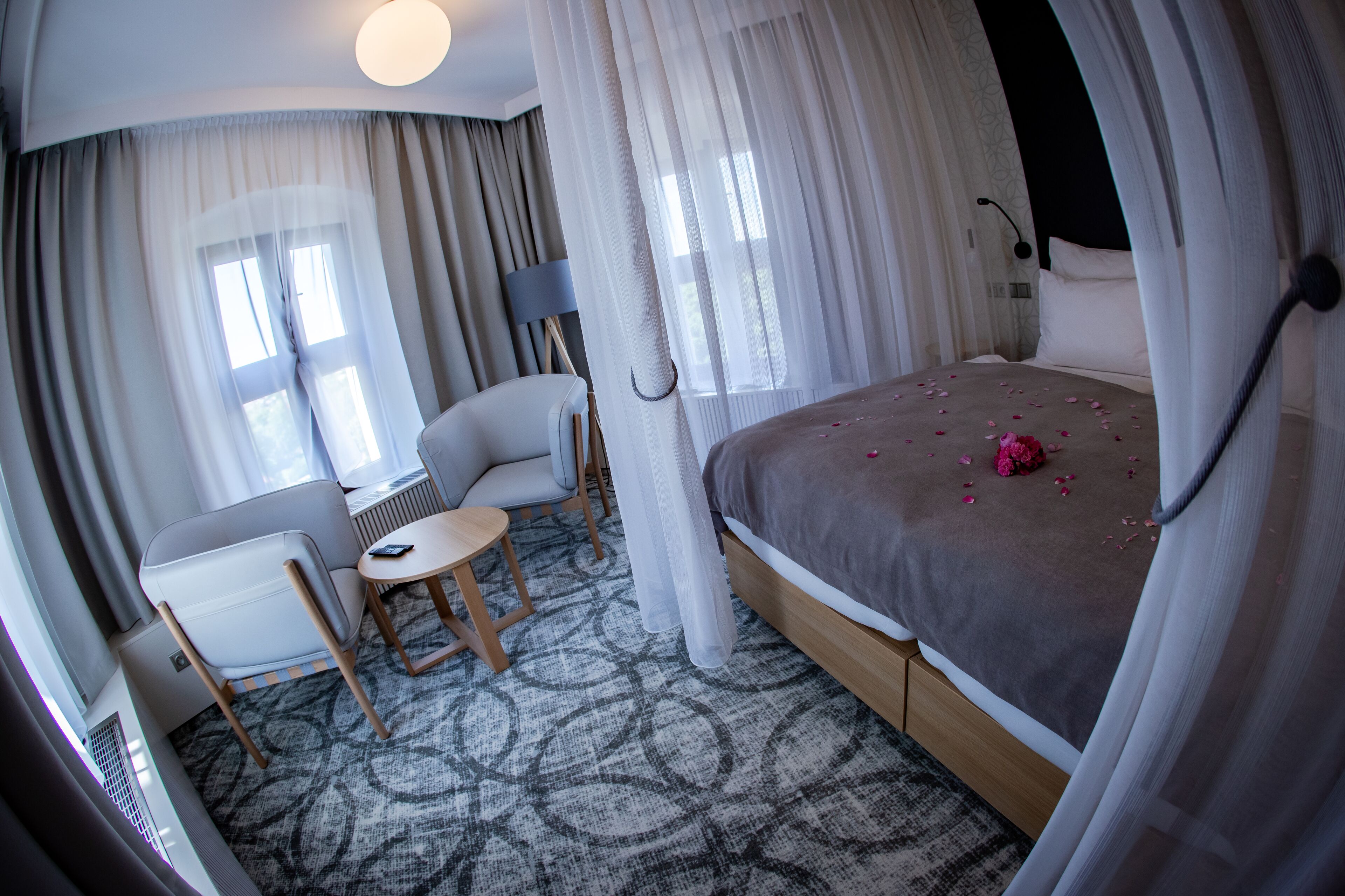 Ein Hotelzimmer mit Bett, Stuhl, kleinem Tisch und einer Lampe.