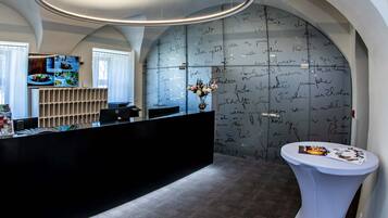 A reception area with a black reception desk, a white side table, and a wall with handwritten notes.