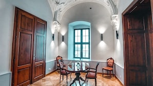 A room with a wooden parquet floor, a round table with chairs, and a large window with a view. - Chateau Třešť (Trest)