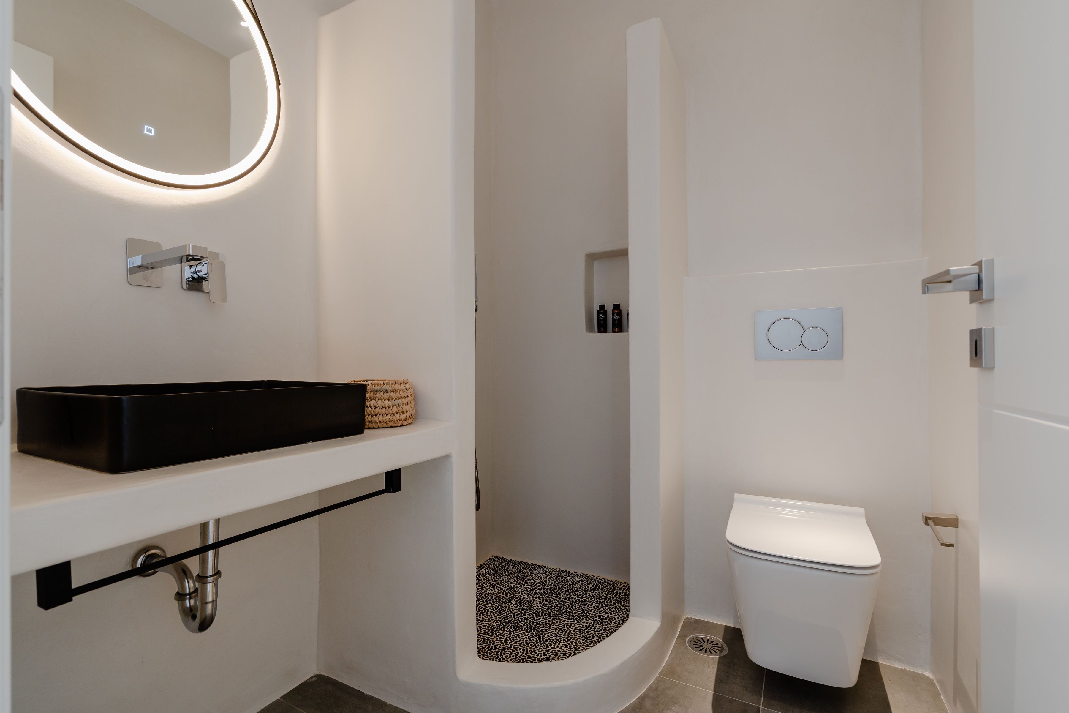 A modern bathroom with a black sink, a toilet, and a shower with a leopard print floor.