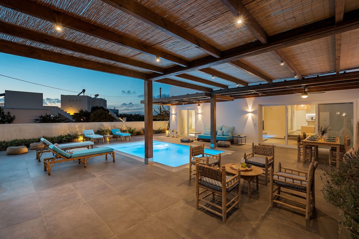 An outdoor patio with a pool, lounge chairs, and dining area under a wooden pergola.