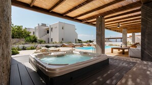 A hot tub under a wooden pergola with a pool in the background. - Citrus Seaside Houses (Naxos)