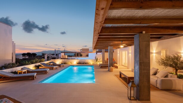 A modern outdoor pool area with lounge chairs and a wooden pergola. - Citrus Seaside Houses (Naxos)