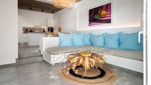 A modern living room with a white sofa, blue cushions, and a unique wooden coffee table. - Citrus Seaside Houses (Naxos)