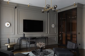 A modern living room with a large flat-screen TV, a round coffee table, and a seating area with a sofa and chairs. - A22 Hotel (Riga)