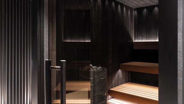 Een moderne spa met houten banken en een stenen muur.