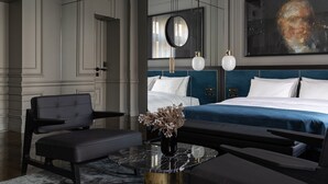 Een moderne slaapkamer met een groot bed, een bureau, een stoel en een schilderij aan de muur.