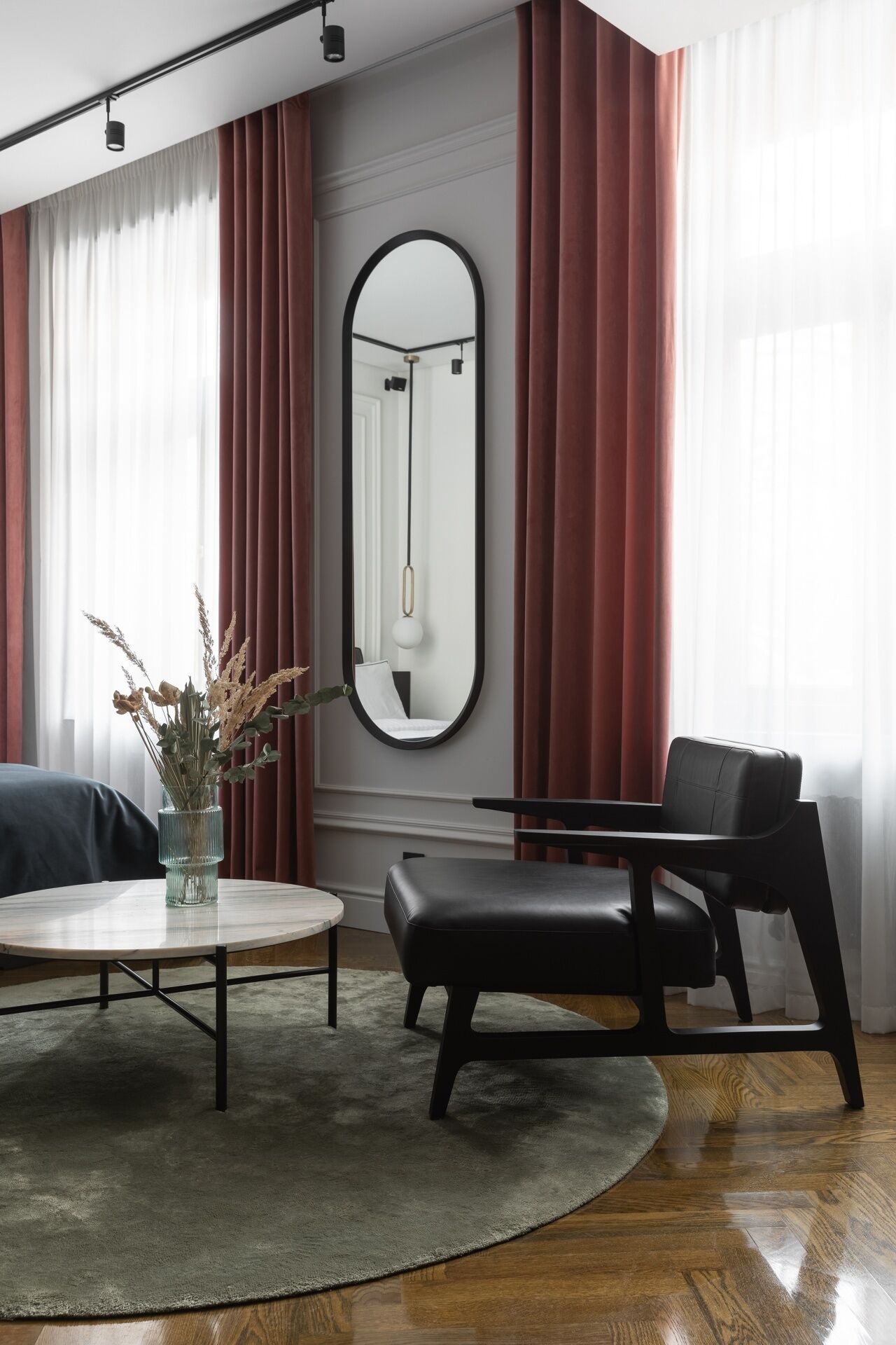 Una habitación moderna con una mesa redonda, un banco de cuero negro y un espejo grande en la pared.