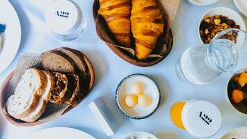 Una mesa dispuesta con diferentes productos para el desayuno, como bollería, pan y diversas mermeladas.