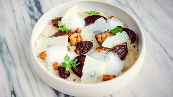 A bowl of food with figs, nuts, and cheese on a marble surface.