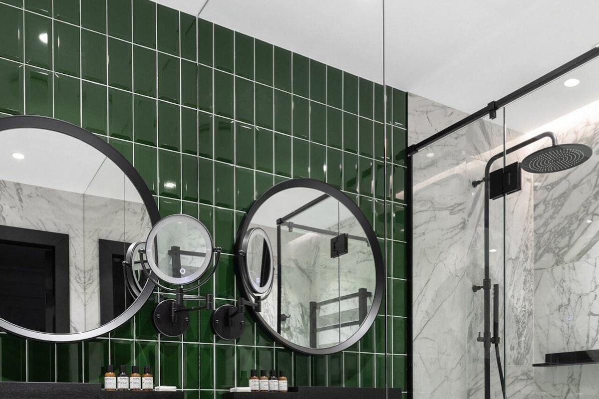 A modern bathroom with two round mirrors, a large sink, and a walk-in shower.