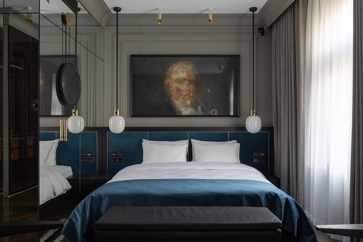 Une chambre d’hôtel moderne avec un grand lit, un tableau au mur et une grande fenêtre avec des rideaux.