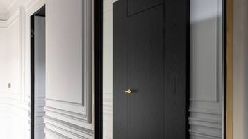 A hallway with a dark wooden door and a large mirror reflecting the door.
