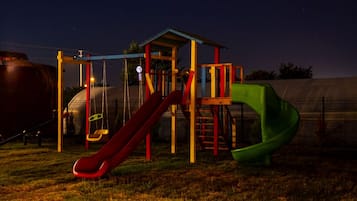 Kids can play on the slide and swing set in this grassy playground area.