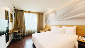 A hotel room with a bed, a desk with a chair, a TV, and a phone. - Alivaa Hotel, Millennium City Center, Sector 29, Gurugram (Gurugram)