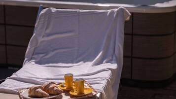 Une chaise longue, avec un plateau rempli de viennoiseries et deux tasses jaunes, placée devant une piscine.