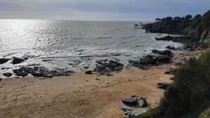 En strand med stenig mark och fri utsikt över havet.