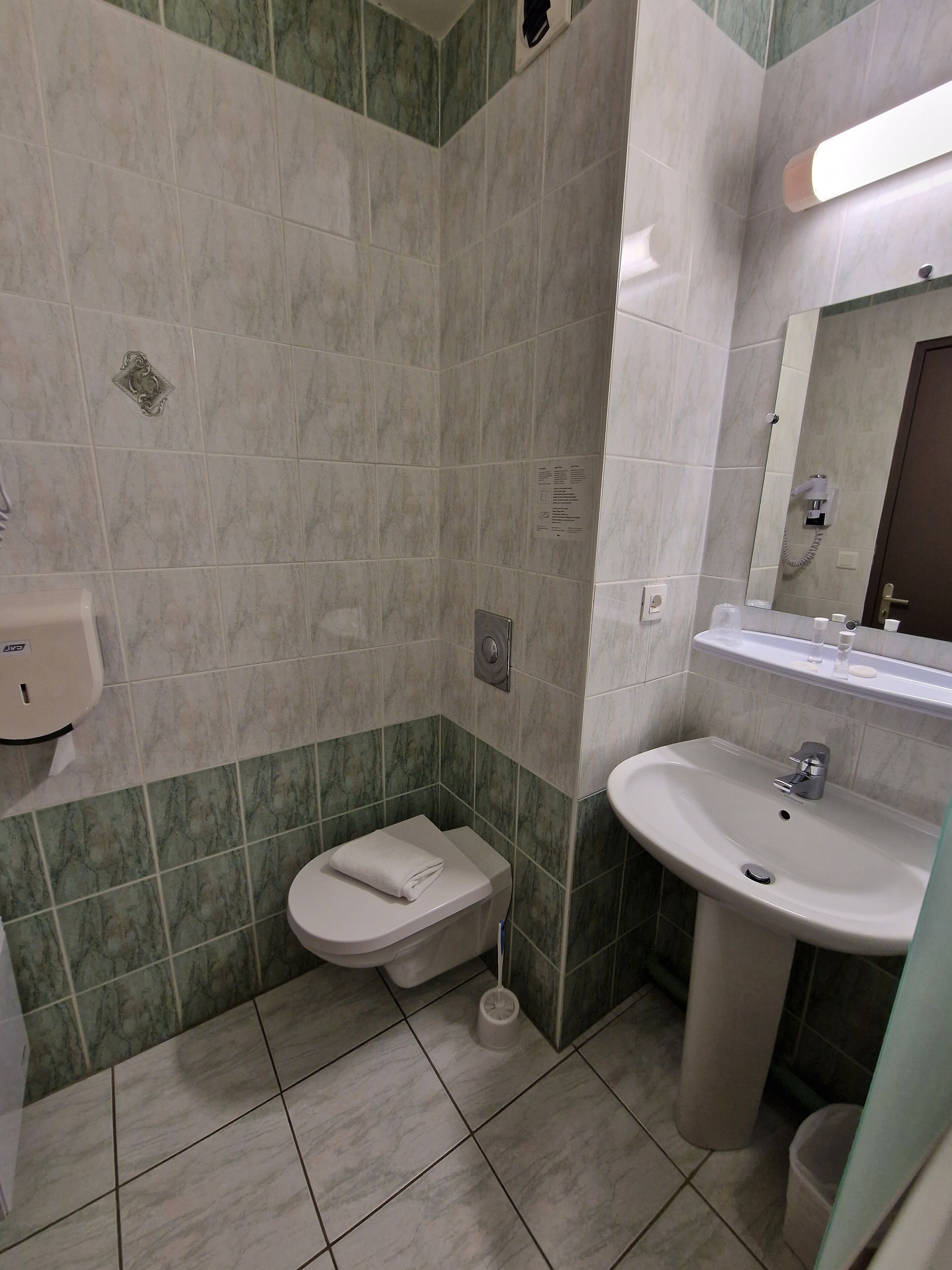 Een badkamer met toilet, wastafel en spiegel.