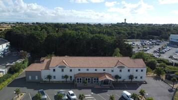 Un hotel con tetto in tegole, diverse finestre e un parcheggio.