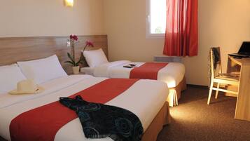 A hotel room with two beds, a desk, a chair, a potted plant, and a window with curtains.