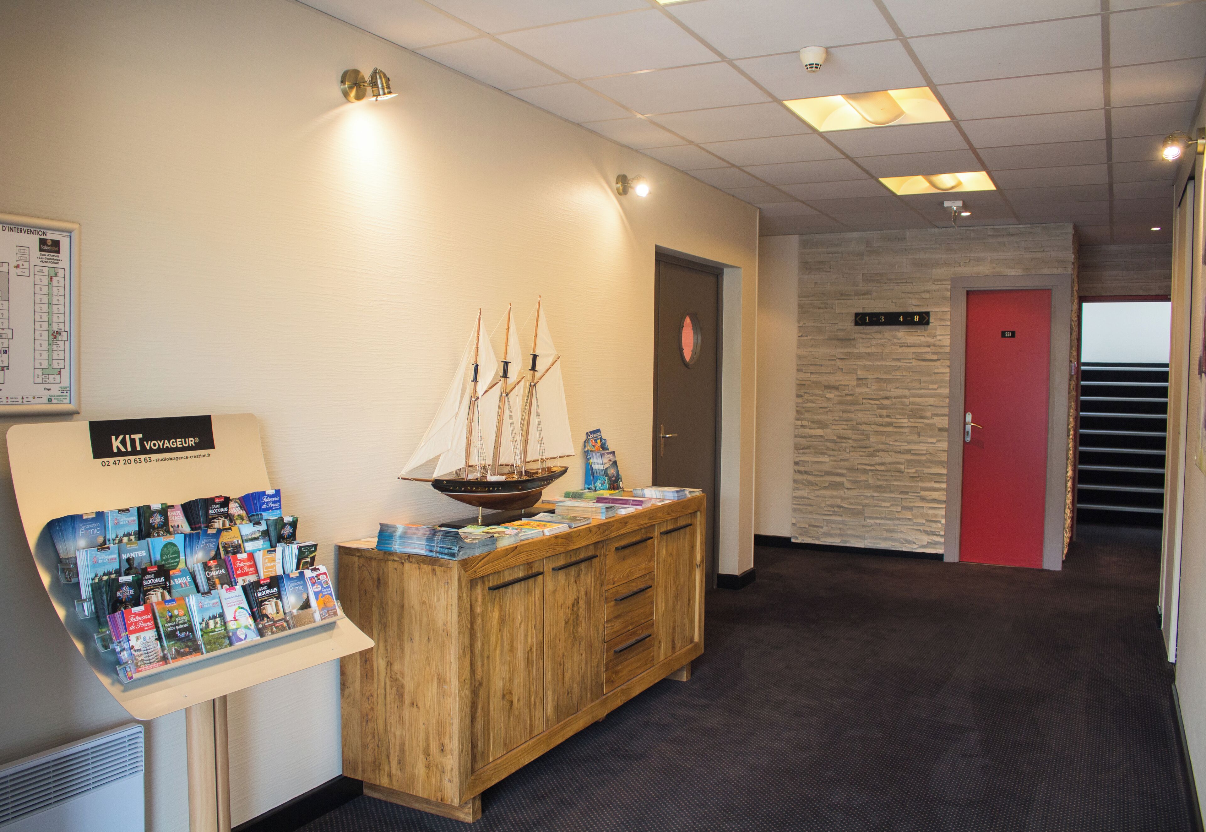 A reception desk with a wooden cabinet, a ship model, and a brochure stand.