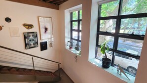A staircase with a metal railing, a window with a potted plant, and various framed artworks on the wall. - Central New York-Style Loft with parking - Inner City Apartment - Chippendale (Chippendale)