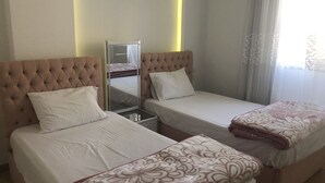 Habitación de hotel con dos camas, cada una con cabecera, mesita de noche y espejo.