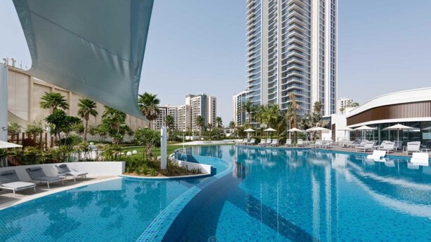 Un hotel moderno con una grande piscina, palme e grattacieli sullo sfondo.