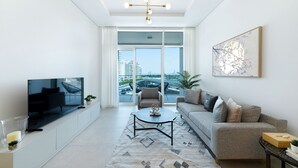 Un soggiorno moderno con una TV a schermo piatto, un divano, un tavolino da caffè e un'ampia finestra con vista sulla città.
