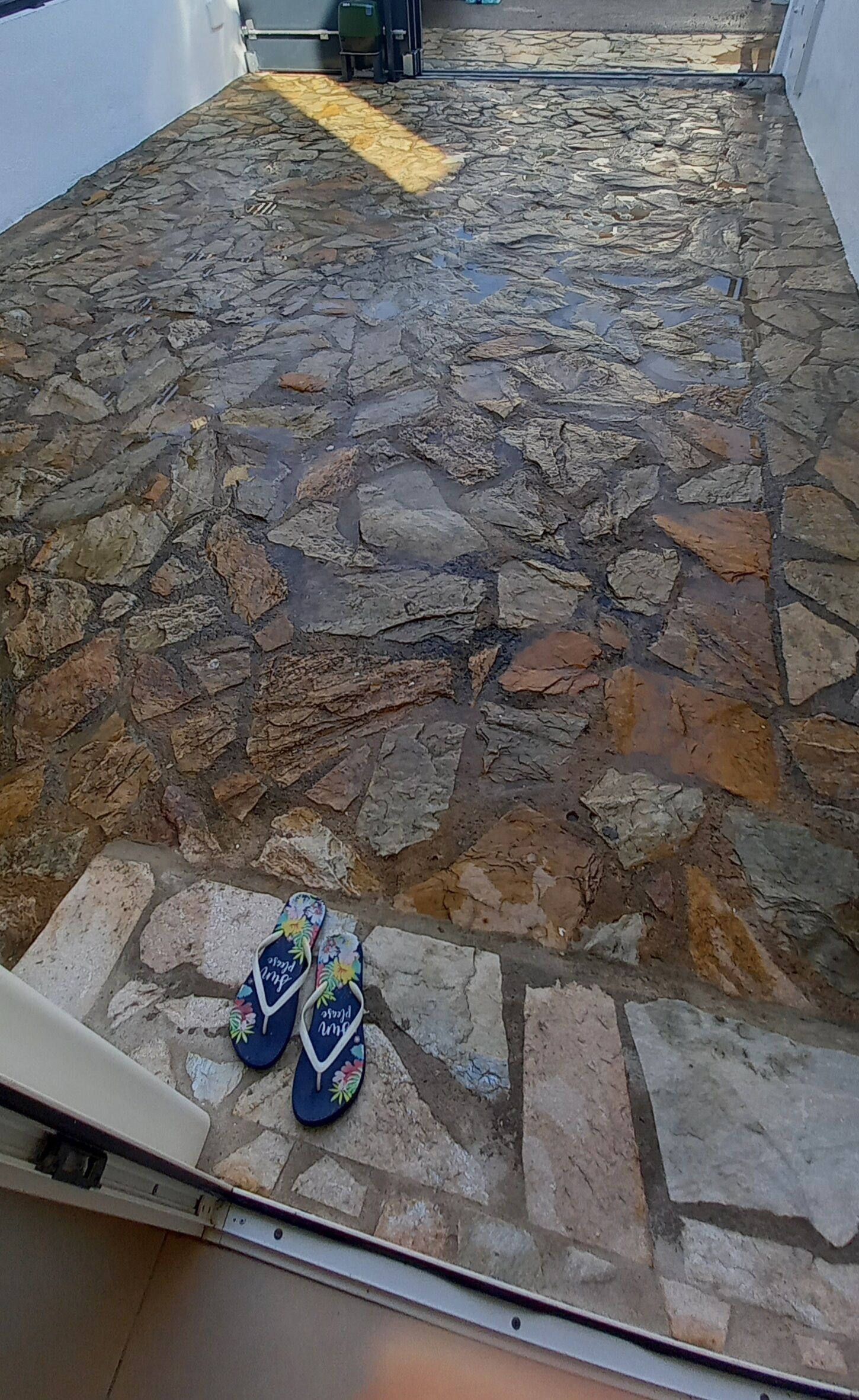 A stone-paved courtyard with a pair of colorful flip-flops on the ground.