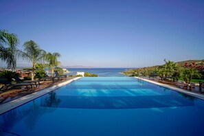 A large, clear swimming pool with lounge chairs and palm trees, overlooking a coastal view. - Cape Krio Boutique Hotel & Spa - over 12 years old Adult Only (Datça)