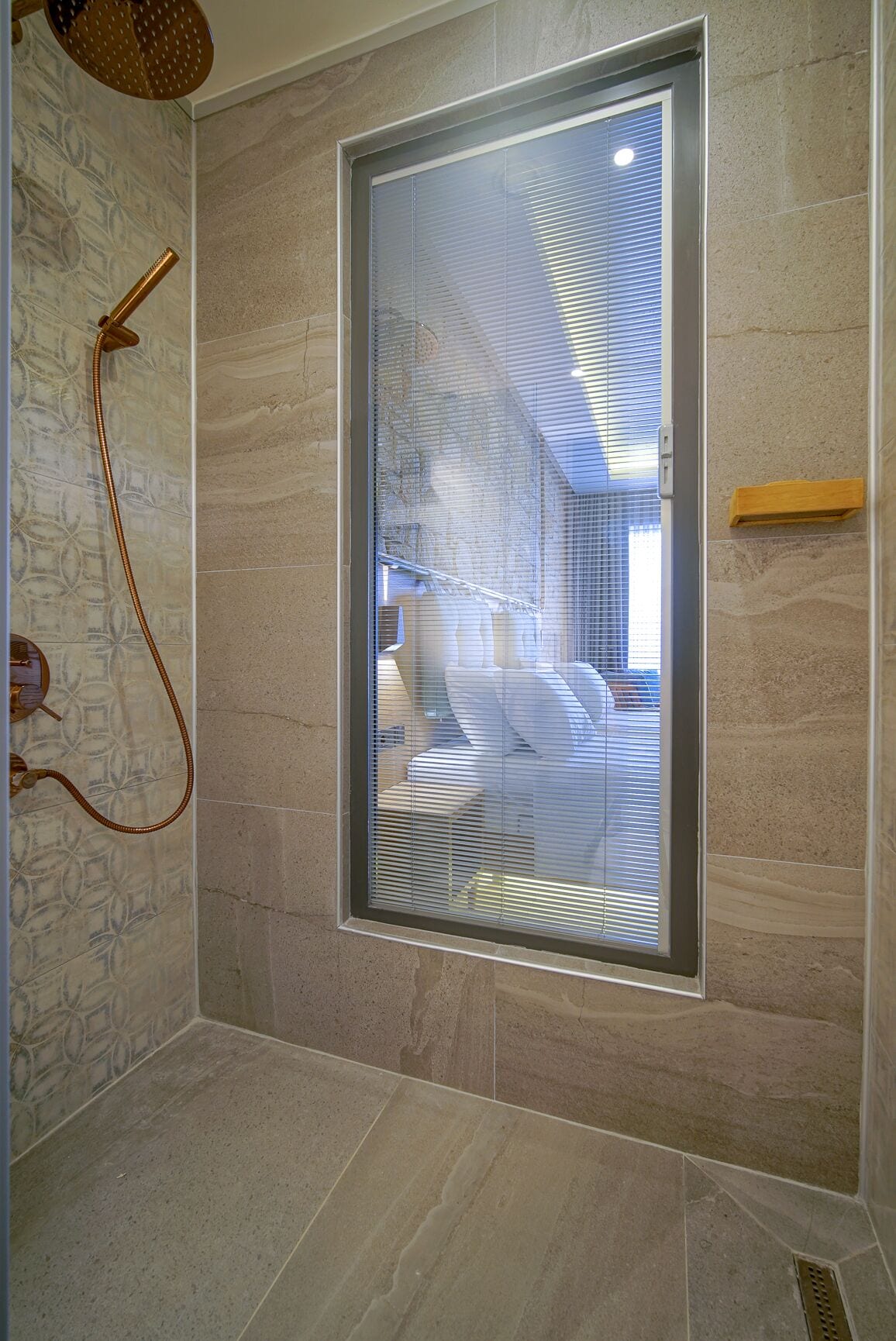 Une douche avec une porte en verre, un pommeau de douche amovible et un porte-serviettes.