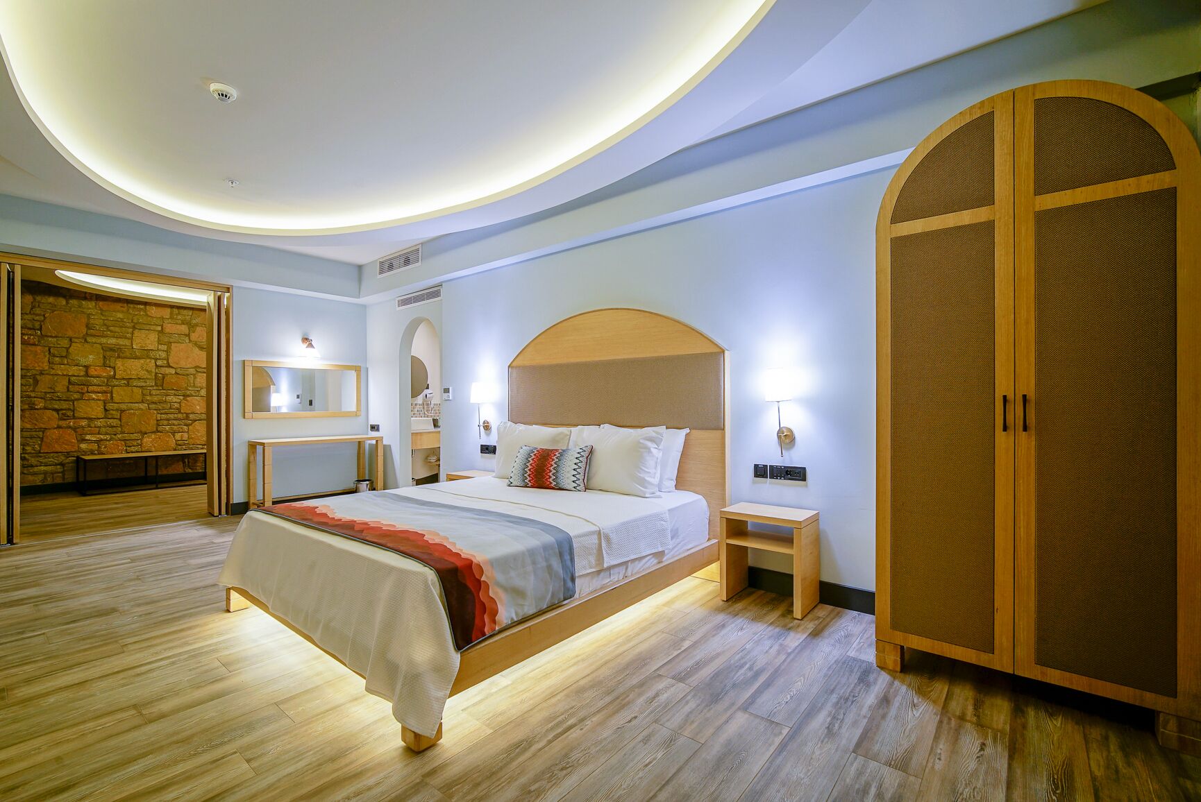 Een moderne slaapkamer met een groot bed, een houten kledingkast en een stenen muur.