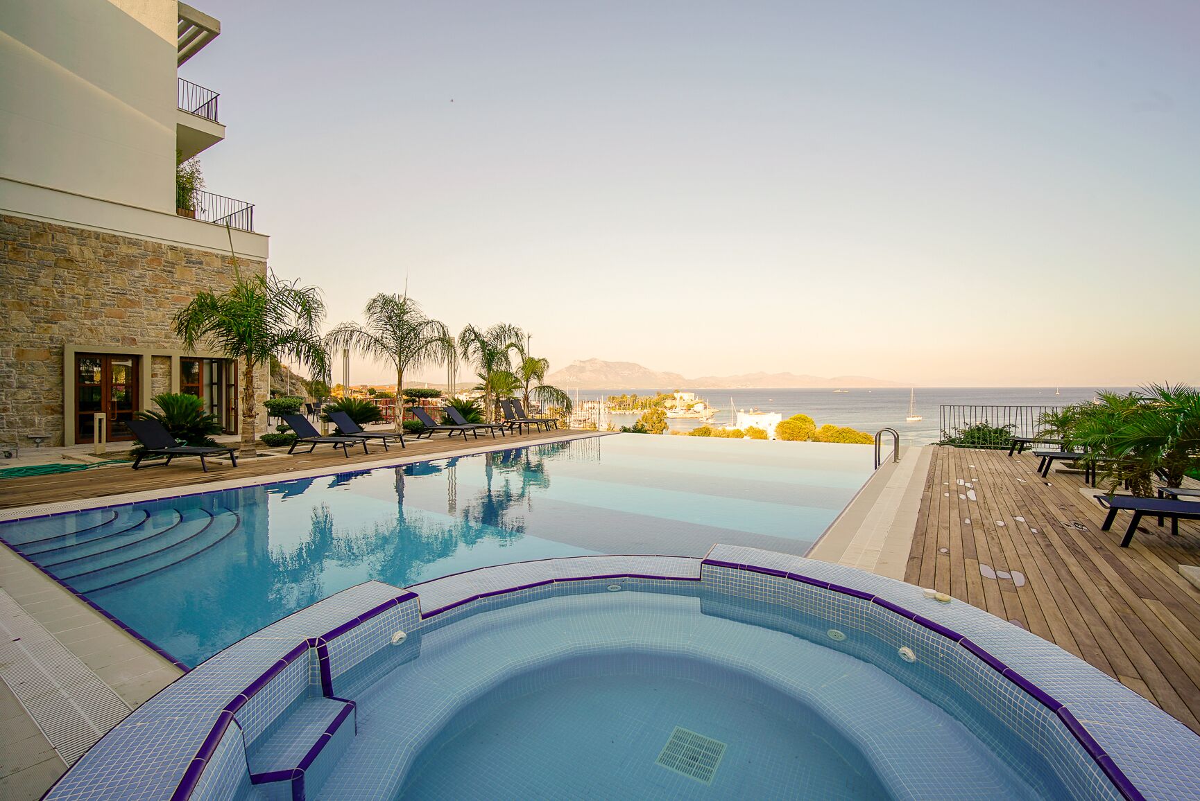 A swimming pool with lounge chairs and a view of the sea.