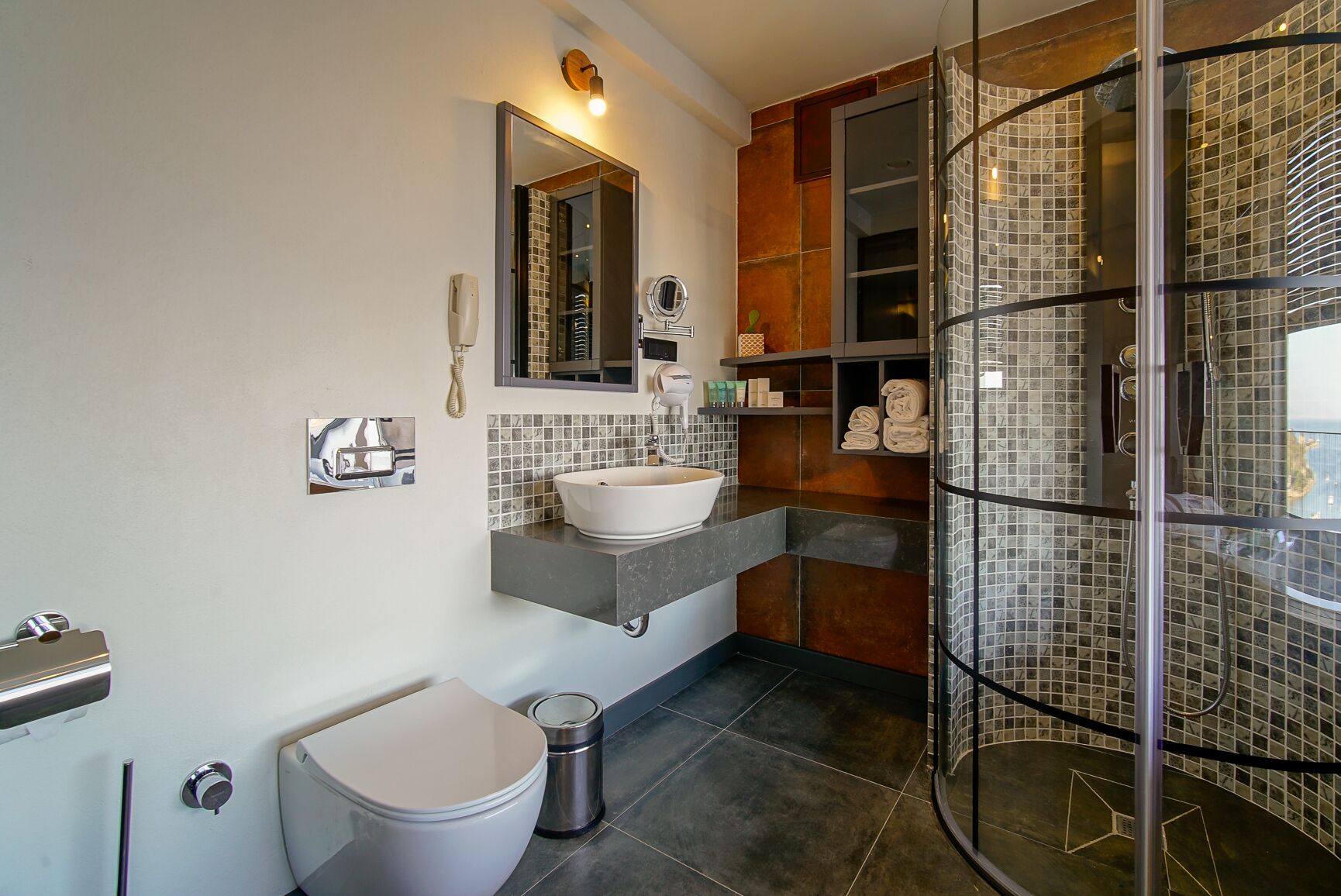 A modern bathroom with a glass-enclosed shower, a white sink, and a toilet.