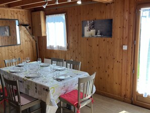 Un coin repas avec un décor intérieur en bois, une table dressée pour quatre personnes et un tableau accroché au mur.