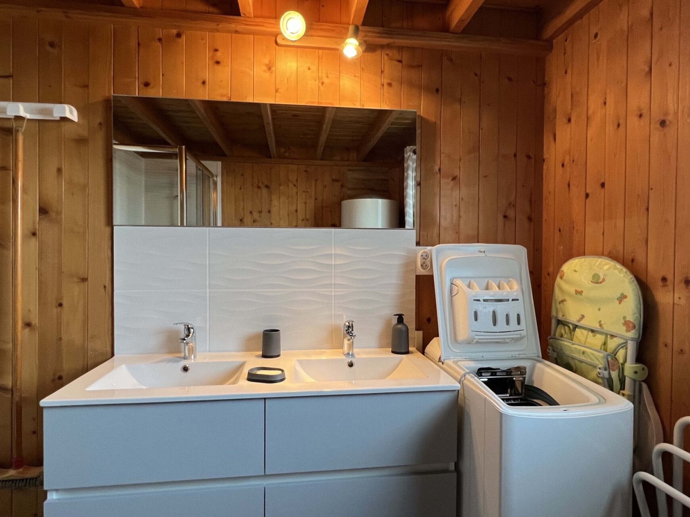 A wooden cabin bathroom with two sinks, a mirror, and a shower.