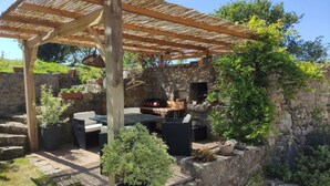 An outdoor patio with a pergola, stone walls, and potted plants. - Charming house 1km from Sciotot beach (Les Pieux)