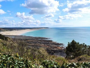 Un paisaje costero con una playa, costa rocosa y vegetación.
