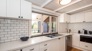 Una cocina moderna con gabinetes blancos, un lavamanos de acero inoxidable y un horno empotrado.
